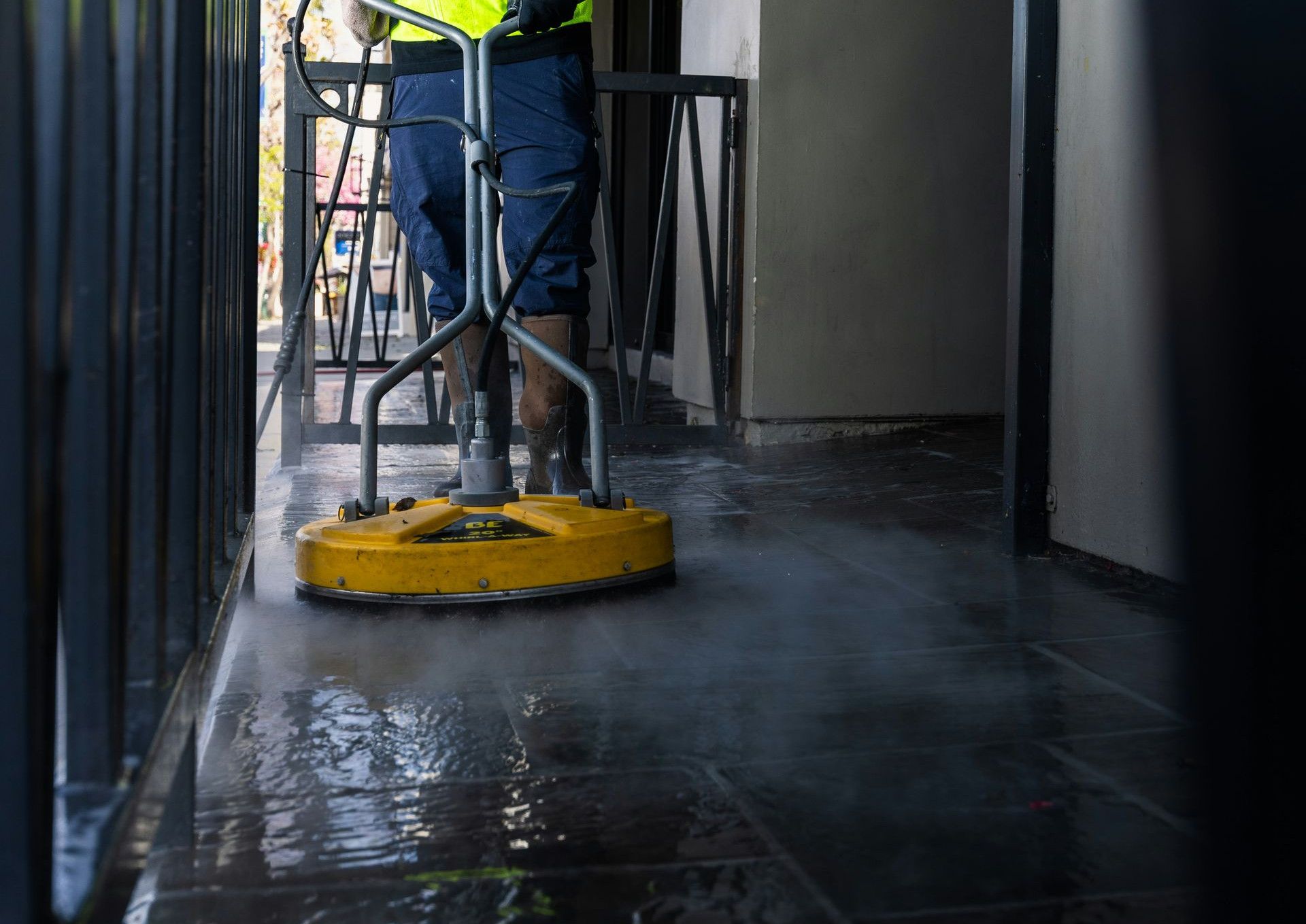 a man in a yellow vest is cleaning the floor
